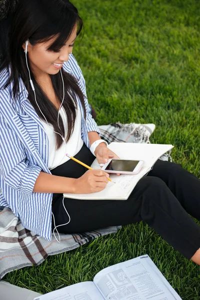 Draufsicht auf charmante asiatische Studentin, die Notizen macht, während li — Stockfoto