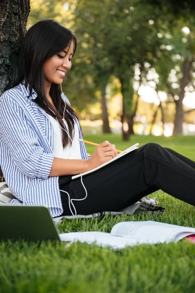 Pretty chinese female student listening to music, while studying — Stock Photo, Image