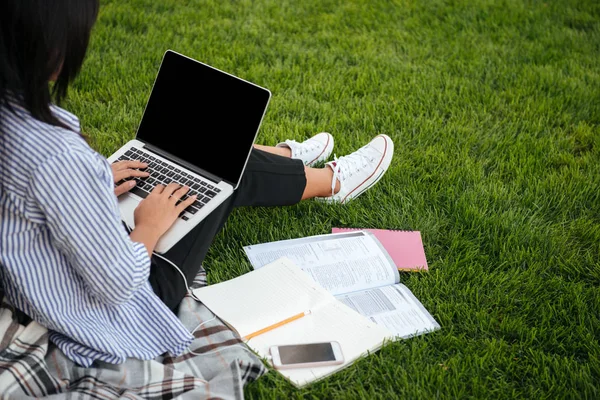 Vue recadrée d'une étudiante tapant sur ordinateur portable, assise sur gras — Photo