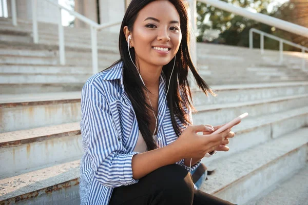 Close-up foto van vrij lachende Aziatische vrouw in witte oortelefoons — Stockfoto