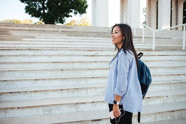 Voltar visão de muito sorrindo mulher asiática com mochila indo para cima s — Fotografia de Stock