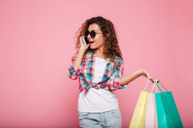 Smartphone üzerinde konuşmak ve izole çanta holding neşeli kadın