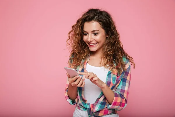 Mujer alegre usando teléfono inteligente aislado sobre rosa —  Fotos de Stock