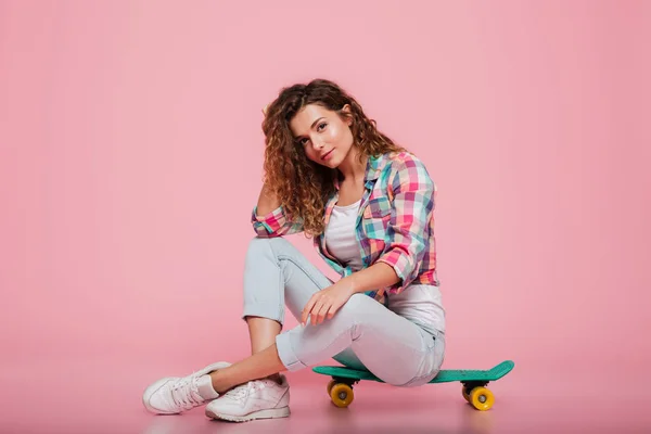 分離されたスケート ボードの上に座って若いきれいな女性 — ストック写真