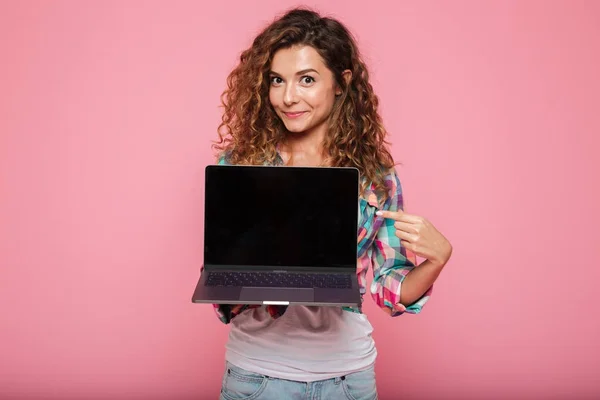 Giovane signora che indica lo spazio di copia sul computer portatile isolato su rosa — Foto Stock
