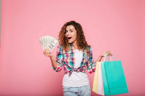 Happy woman with money and shopping bags posing isolated