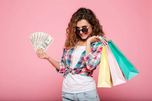 Gelukkige vrouw met geld en boodschappentassen poseren geïsoleerd — Stockfoto