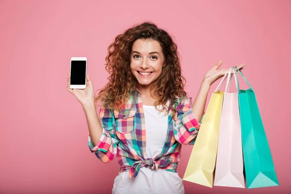 Joven dama feliz sosteniendo bolsas de compras y teléfono inteligente — Foto de Stock