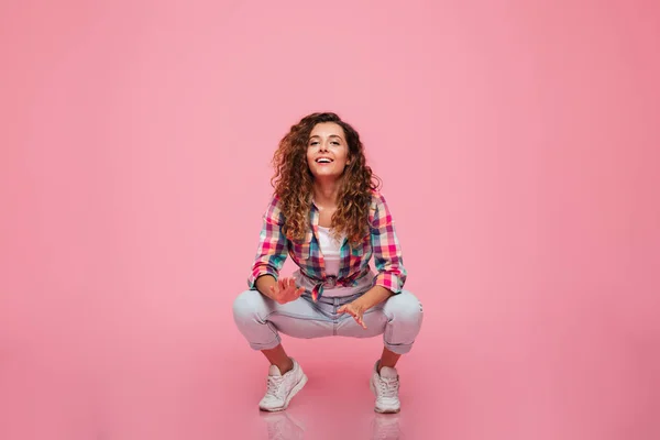 Senhora engraçada agachamento e sorrindo para câmera isolada — Fotografia de Stock