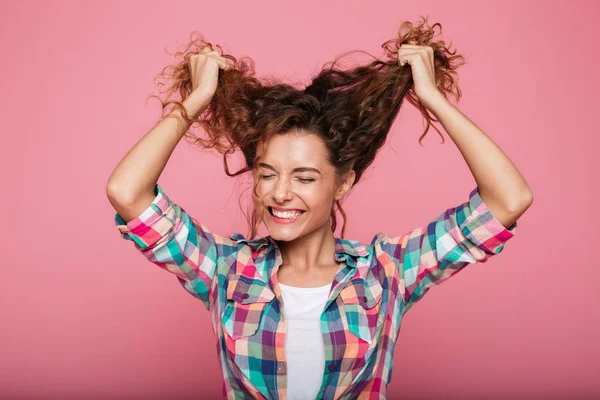 Joven dama sonriente jugando con el pelo rizado y riendo aislado —  Fotos de Stock