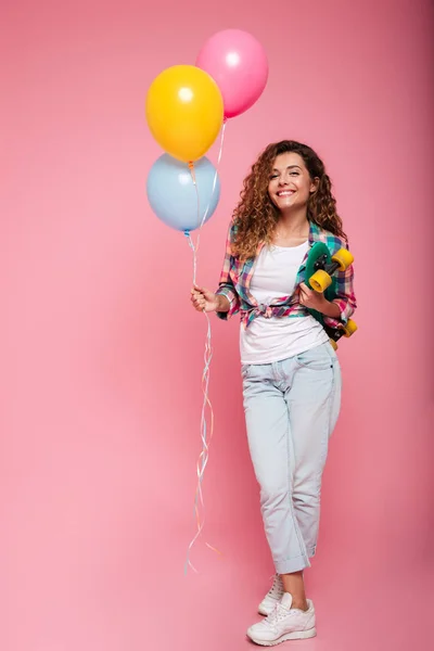 Tirador de cuerpo entero de mujer sosteniendo globos de aire y monopatín aislados — Foto de Stock