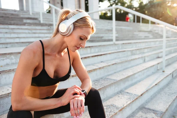 Sterke jonge sport vrouw met behulp van horloge buitenshuis — Stockfoto