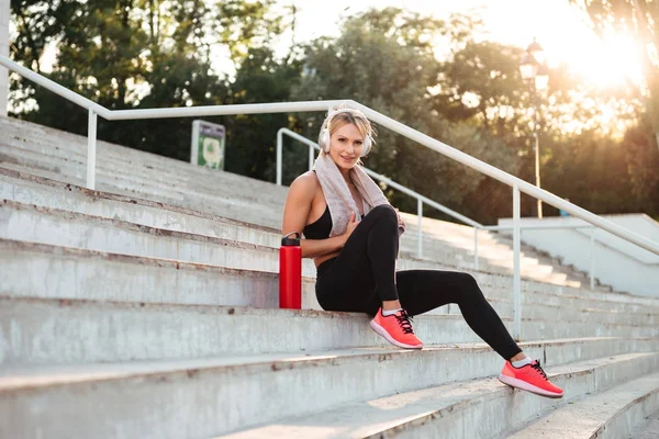 Ziemlich starke junge Sportlerin, die Musik hört — Stockfoto