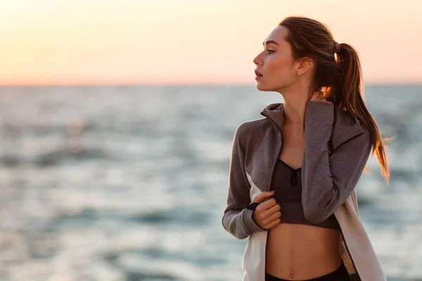 Joven mujer deportiva encantadora descansando después del entrenamiento, mirando a un lado — Foto de Stock