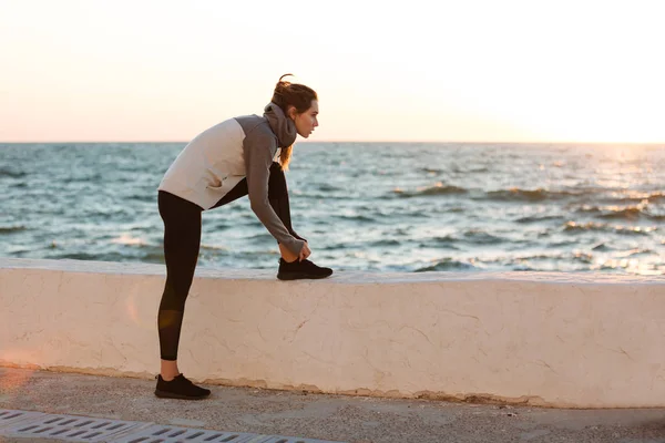 Retrato de una joven mujer deportiva delgada atando cordones por la mañana — Foto de Stock