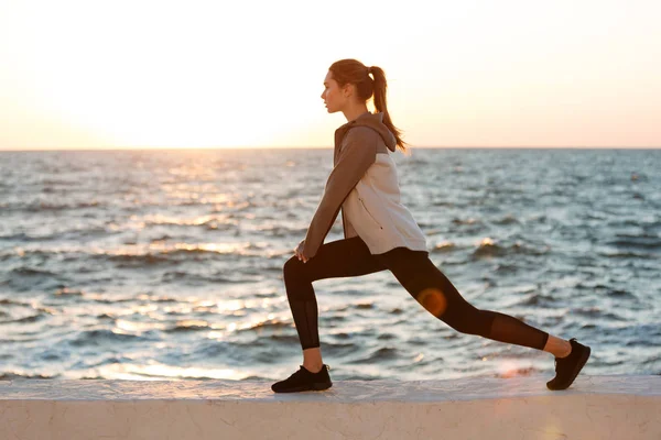 Foto de mujer joven en forma haciendo ejercicio de estiramiento en el mar — Foto de Stock