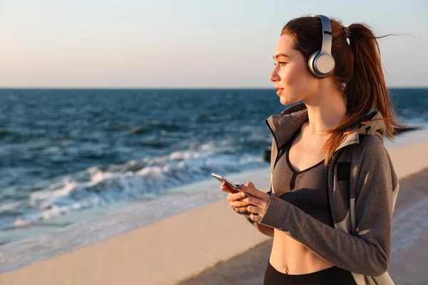 Foto di giovane donna sportiva bruna che ascolta musica in grigio h — Foto Stock