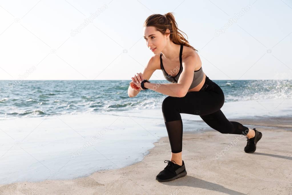 Portrait of young smiling  fitness woman checking time while doi