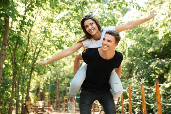 Young smiling couple enjoying piggyback ride and laughing — Stock Photo, Image