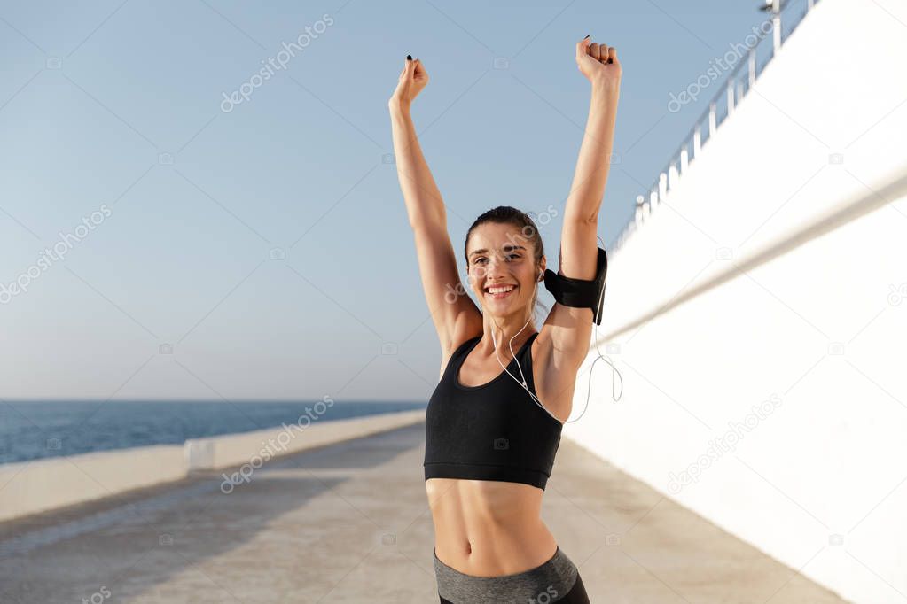 Cheerful woman training near sea