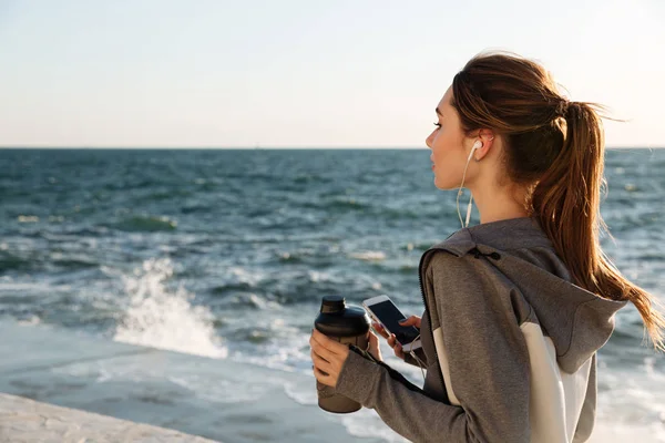 Вид ззаду молода брюнетка спортивна жінка тримає пляшку води — стокове фото