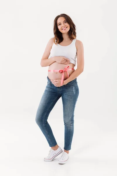Беременная женщина, стоящая в изоляции с луком на животе — стоковое фото