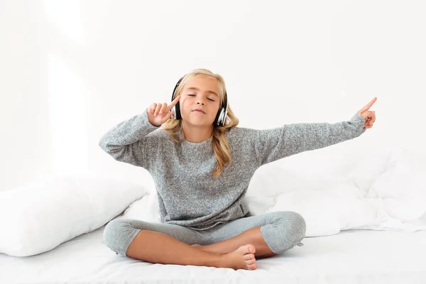 Linda niña en pijama gris escuchando música con cerrado — Foto de Stock