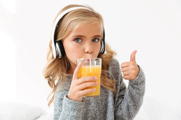 Primer plano retrato de linda chica en los auriculares beber naranja jui — Foto de Stock