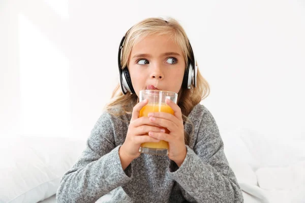 Foto de cerca de la niña bonita en los auriculares lamiendo mientras — Foto de Stock