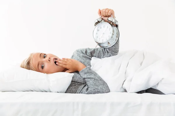Удивительная маленькая блондинка держит будильник, прикрывая своего мута — стоковое фото