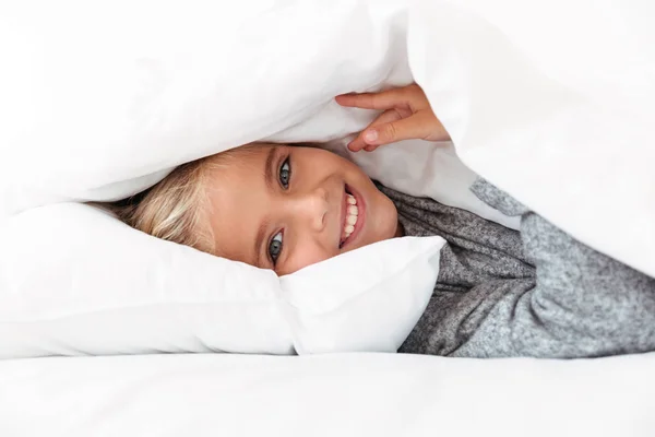 Крупный план улыбающейся маленькой девочки с подарком в постели — стоковое фото
