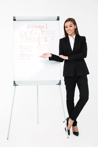 Cheerful pretty businesswoman near business plan showing it. — Stock Photo, Image