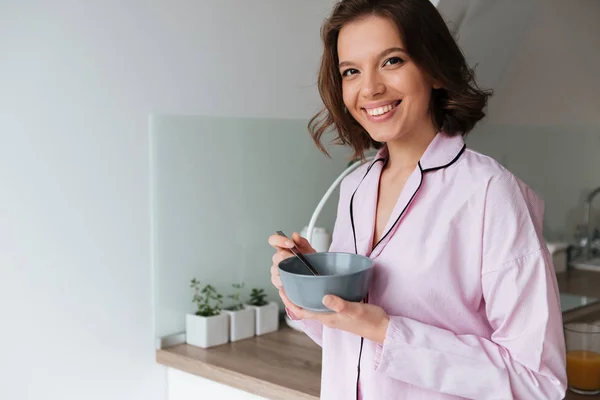 Retrato de una joven sonriente en pijama desayunando — Foto de Stock