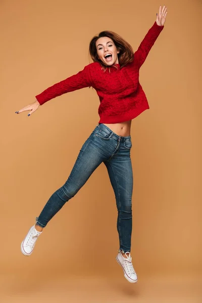 Усміхнена біла жінка, одягнена в светр, стрибає — стокове фото