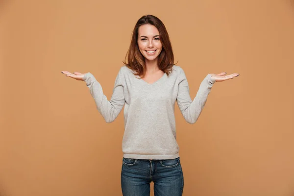 Gelukkig jonge brunette vrouw in grijze blouse en jeans tonen twee — Stockfoto