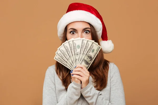 Caucasian shocked lady wearing christmas hat holding money. — Stock Photo, Image