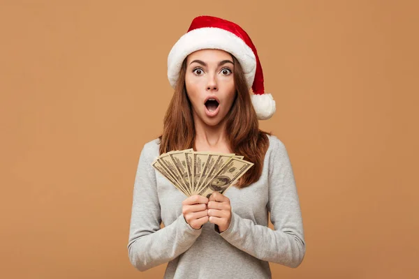 Caucasian shocked lady wearing christmas hat holding money. — Stock Photo, Image