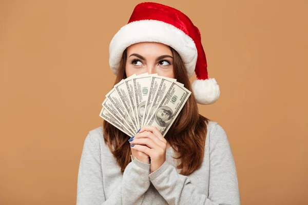 Hvid dame iført julehat holder penge . Stock-billede