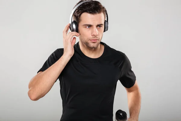 Porträtt av en allvarlig stilig sportsman lyssnar på musik — Stockfoto