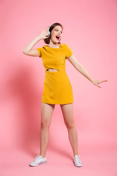 Vzrušený šťastná mladá dáma ve žlutých šatech tančí — Stock fotografie