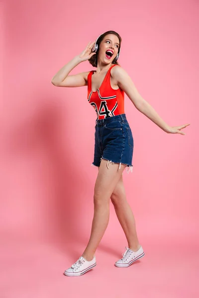 Excited emotional young lady dancing isolated pink background — Stock Photo, Image