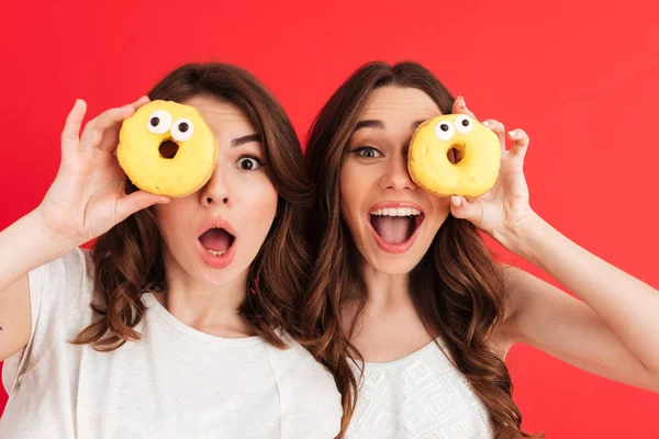 Porträt zweier fröhlicher Mädchen, die mit Donuts posieren — Stockfoto