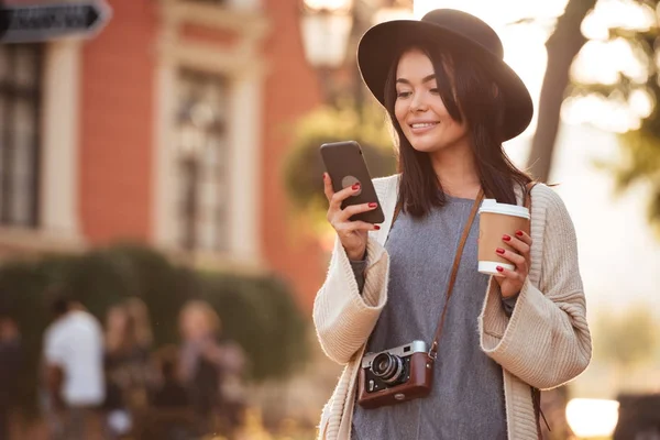 Menina asiática bonita no desgaste moderno usando telefone celular e segurando — Fotografia de Stock