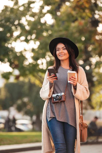 Jovem sorrindo asiático mulher no elegante desgaste segurando smartphone e — Fotografia de Stock