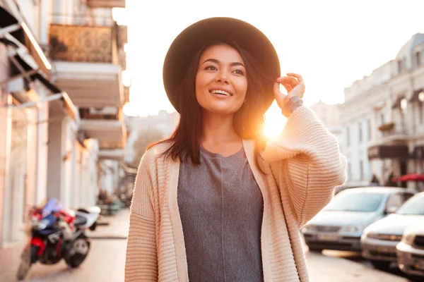 Feliz atraente asiático na moda mulher ajustando seu chapéu enquanto andar — Fotografia de Stock