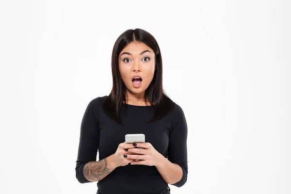 Shocked young asian woman chatting by mobile phone — Stock Photo, Image