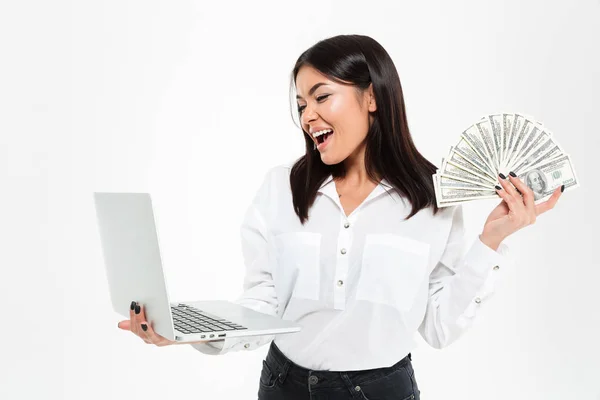 Feliz jovem asiático mulher segurando dinheiro usando laptop computador . — Fotografia de Stock