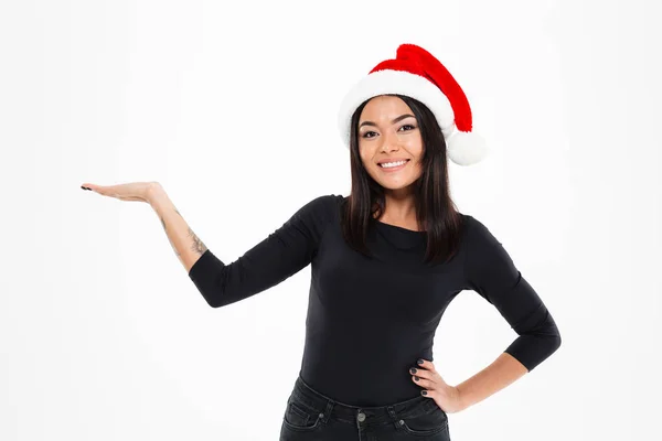 Heureuse femme asiatique portant chapeau de Noël tenant copyspace à la main . — Photo