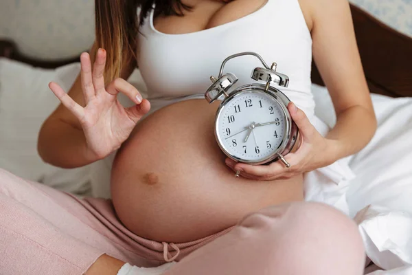 Körülvágott fénykép terhes nő gazdaság ébresztőóra — Stock Fotó
