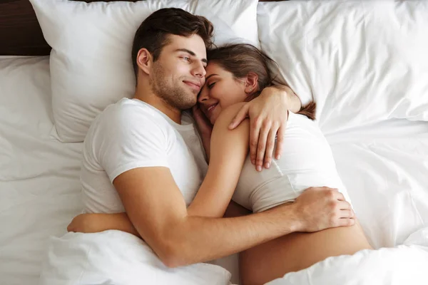 Cheerful pregnant woman lies in bed with husband — Stock Photo, Image